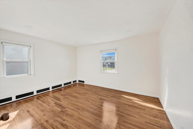 unfurnished room with wood finished floors, baseboards, and baseboard heating