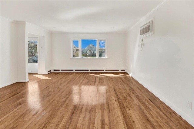empty room featuring a wealth of natural light, crown molding, wood finished floors, and a wall unit AC