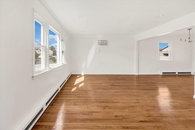 unfurnished room with plenty of natural light, baseboard heating, and wood finished floors