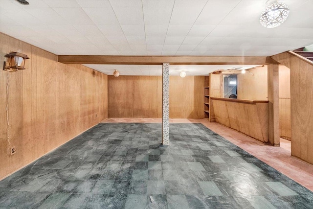 finished below grade area featuring wooden walls and tile patterned floors