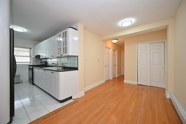 174-20 Jewel Ave, Fresh Meadows, NY 11365 - kitchen featuring range with gas cooktop, dark countertops, baseboard heating, glass insert cabinets, and white cabinetry