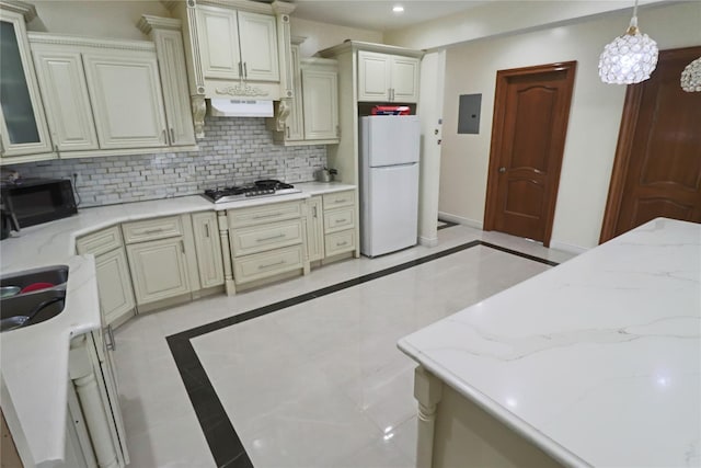 kitchen with electric panel, freestanding refrigerator, gas stovetop, under cabinet range hood, and black microwave