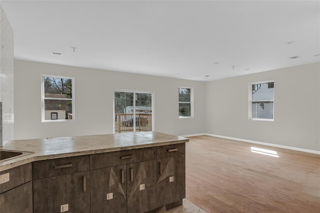 kitchen featuring light countertops, baseboards, dark brown cabinetry, open floor plan, and light wood-type flooring