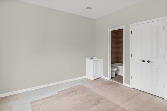 unfurnished bedroom with visible vents, light wood-style floors, a closet, and a sink