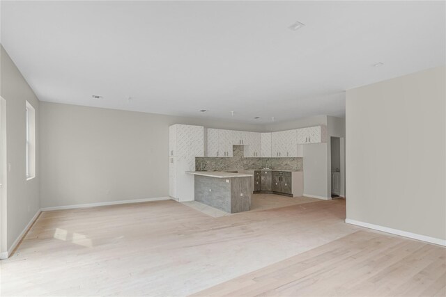 unfurnished living room with baseboards, light wood-type flooring, and visible vents
