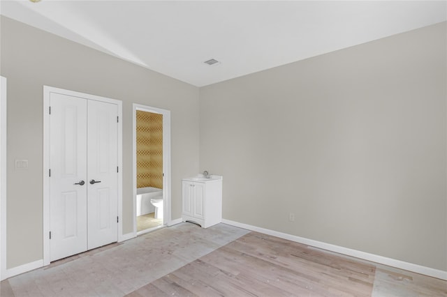 unfurnished bedroom featuring a sink, baseboards, and light wood-style floors