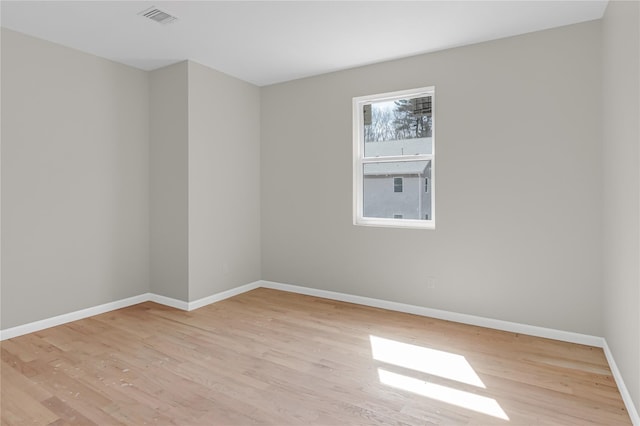 empty room with visible vents, wood finished floors, and baseboards