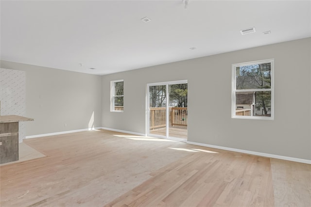 unfurnished living room featuring visible vents, a healthy amount of sunlight, and light wood finished floors