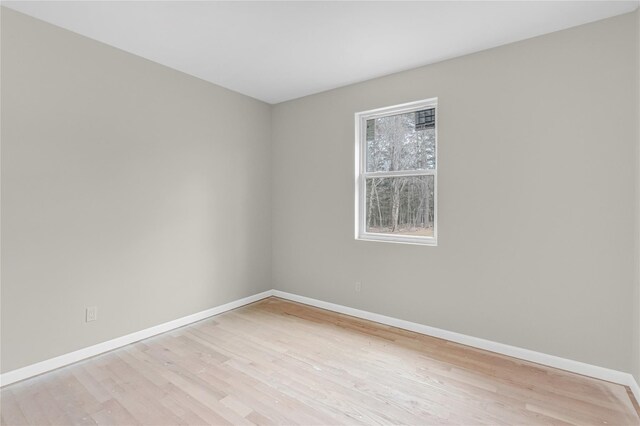 spare room with baseboards and light wood finished floors