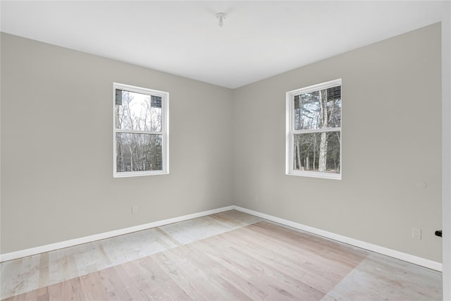 empty room with baseboards, wood finished floors, and plenty of natural light