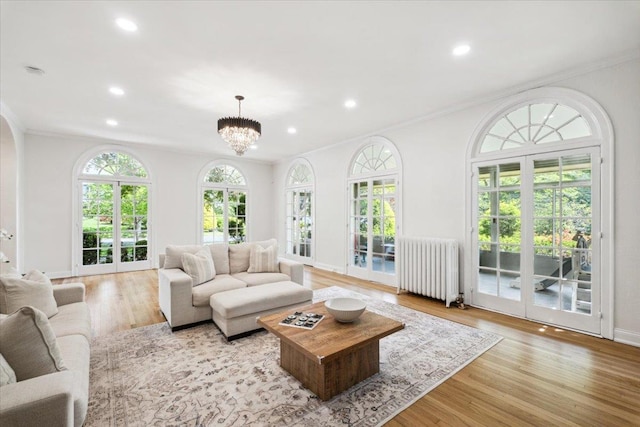 living room featuring radiator, recessed lighting, crown molding, wood finished floors, and a chandelier