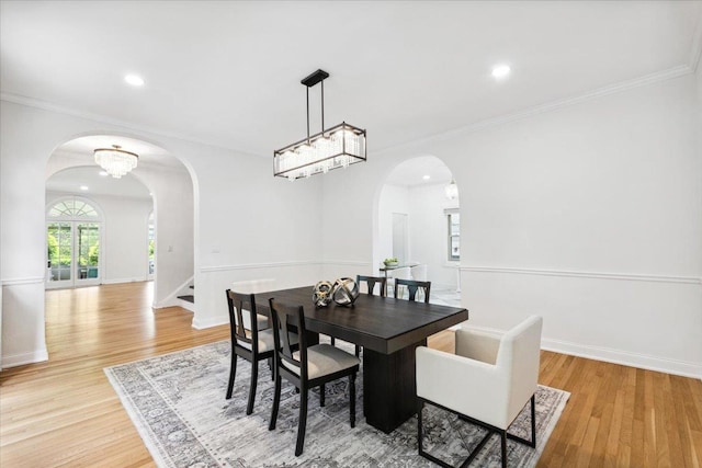 dining space with arched walkways, light wood-type flooring, recessed lighting, crown molding, and baseboards