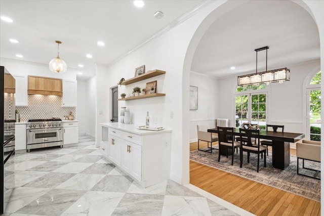 kitchen featuring high end range, arched walkways, recessed lighting, light countertops, and decorative backsplash