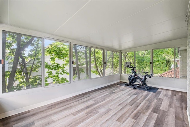 unfurnished sunroom featuring wood finished floors, baseboards, and vaulted ceiling