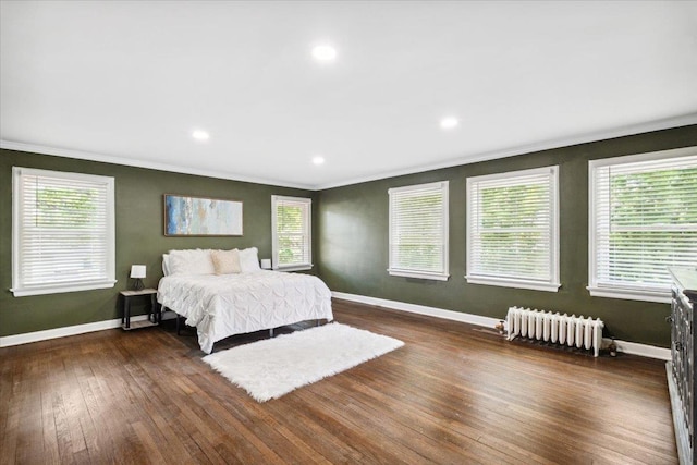 bedroom with radiator heating unit, crown molding, hardwood / wood-style flooring, baseboards, and recessed lighting