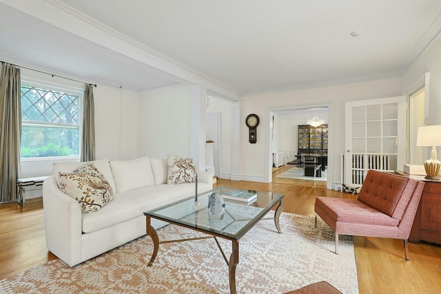 living room with light wood-style flooring, crown molding, and decorative columns