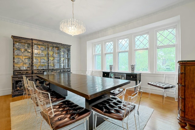 dining space with a chandelier, healthy amount of natural light, light wood finished floors, ornamental molding, and baseboards