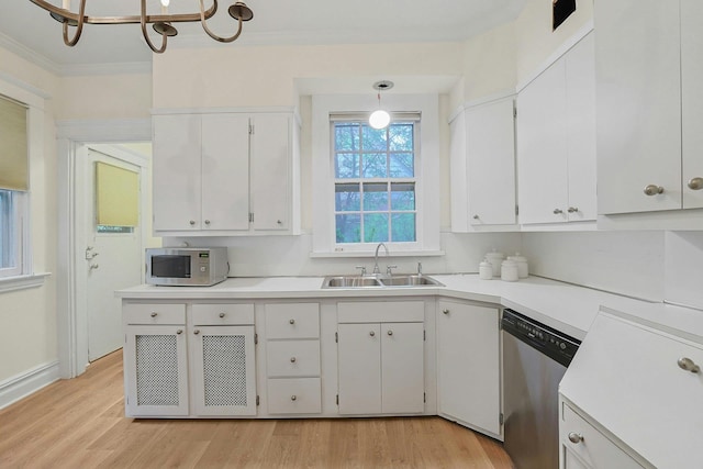 kitchen featuring appliances with stainless steel finishes, a sink, crown molding, light wood finished floors, and white cabinetry