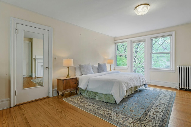 bedroom featuring radiator, wood finished floors, and baseboards
