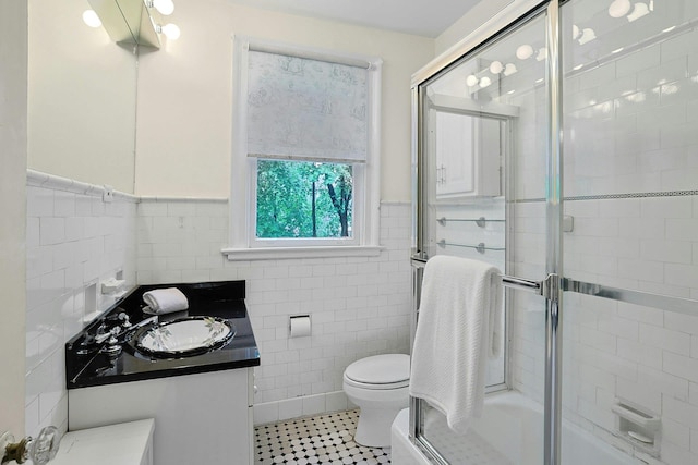 full bathroom with tile walls, vanity, tile patterned flooring, toilet, and wainscoting