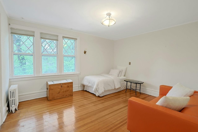 bedroom with radiator heating unit, light wood-style flooring, and baseboards