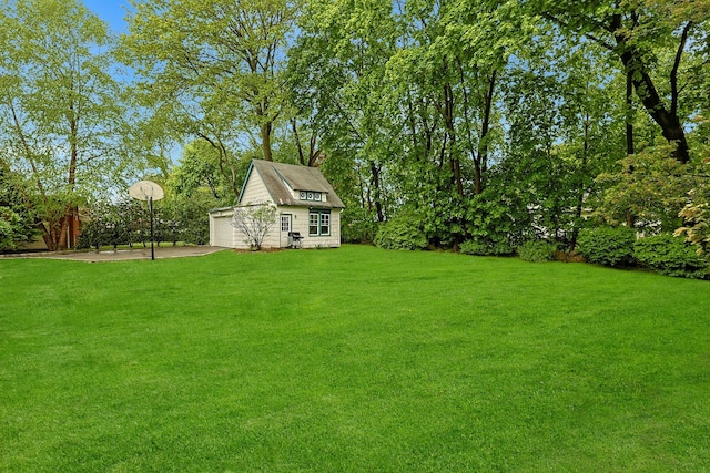 view of green lawn with an outdoor structure and view of wooded area