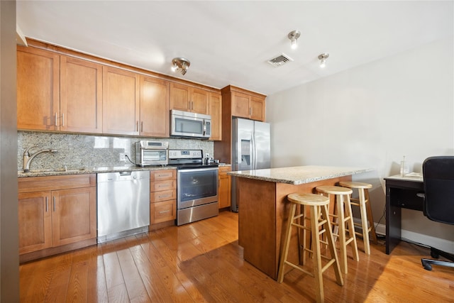 21-25 146th St, Whitestone, NY 11357 - kitchen featuring a sink, light wood-type flooring, stainless steel appliances, a kitchen bar, and visible vents