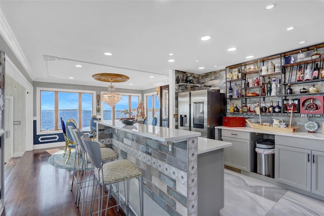 505 E Dr, Copiague, NY 11726 - kitchen featuring ornamental molding, stainless steel fridge with ice dispenser, gray cabinets, light countertops, and a breakfast bar