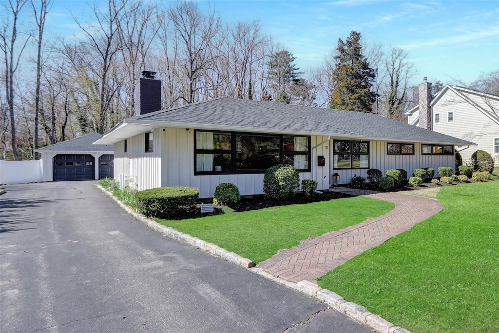 11 Cannon Ct, Huntington, NY 11743 - view of front of house with a front yard, roof with shingles, board and batten siding, and a chimney