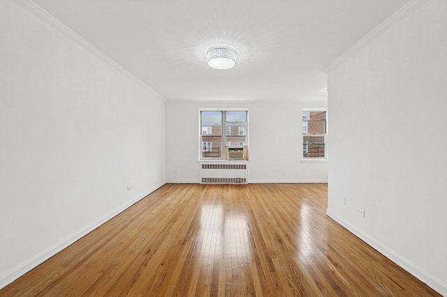unfurnished room featuring radiator heating unit, light wood-style floors, baseboards, and crown molding