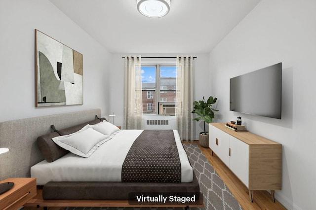bedroom featuring light wood-style flooring, baseboards, and radiator