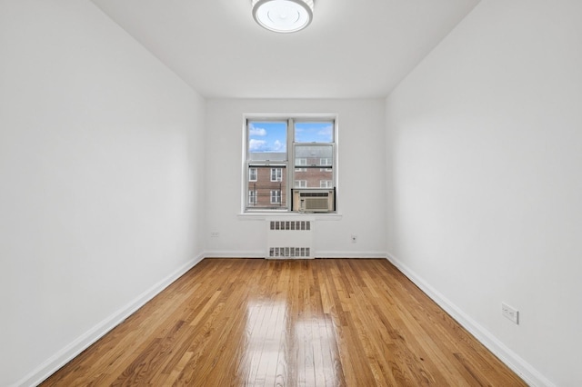 unfurnished room with baseboards, radiator, hardwood / wood-style floors, and cooling unit
