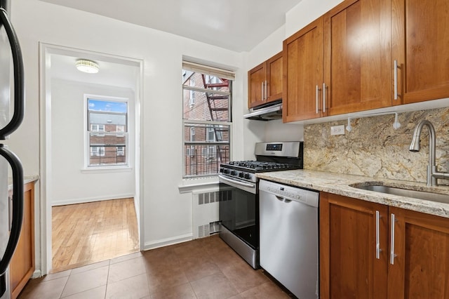 kitchen featuring a sink, brown cabinets, appliances with stainless steel finishes, and under cabinet range hood