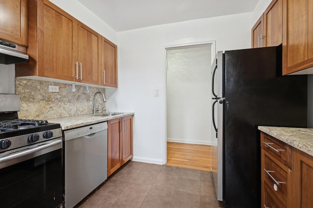 kitchen with exhaust hood, a sink, appliances with stainless steel finishes, backsplash, and tile patterned floors