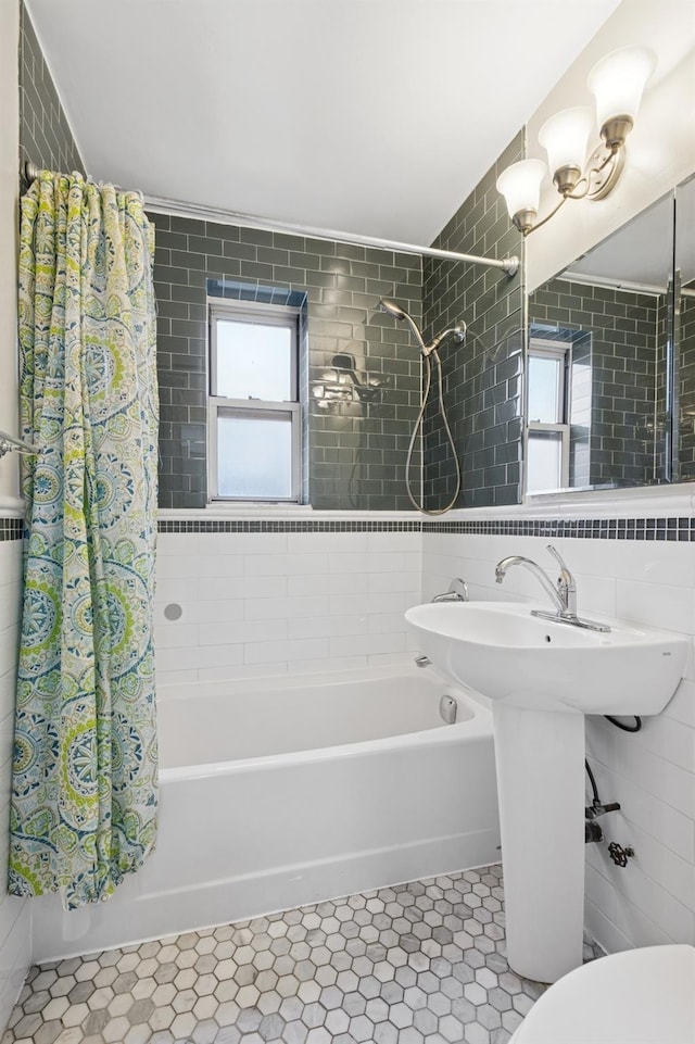 full bath with shower / bath combo, tile patterned floors, and tile walls