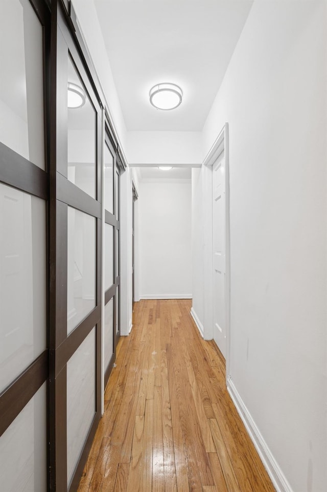 hall with baseboards and light wood-type flooring