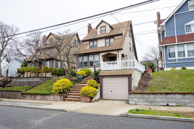tudor house featuring concrete driveway, stairway, a garage, a shingled roof, and covered porch