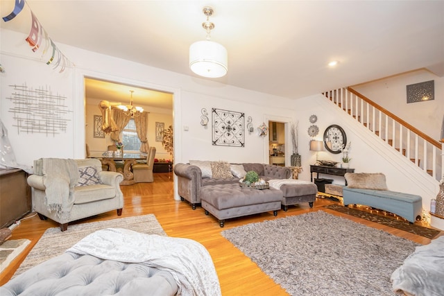 living room featuring stairway, a notable chandelier, and wood finished floors