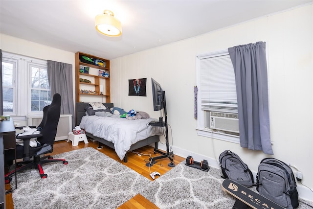 bedroom featuring cooling unit, wood finished floors, and baseboards
