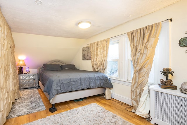 bedroom with lofted ceiling, baseboards, and wood finished floors