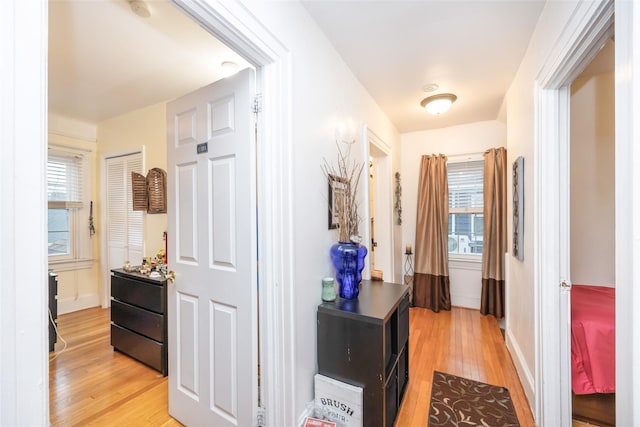 hall featuring light wood-style flooring and baseboards