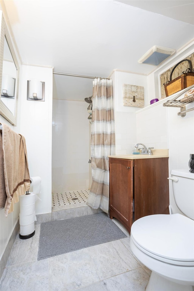 bathroom with tiled shower, vanity, and toilet