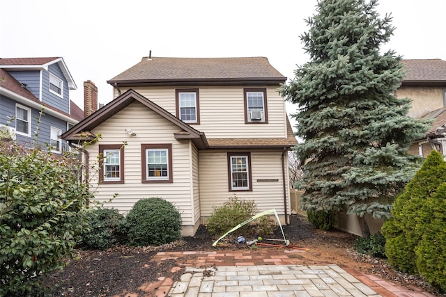 rear view of property featuring a shingled roof