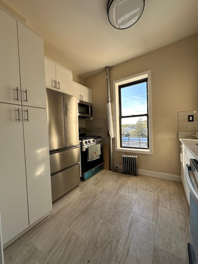 kitchen featuring radiator heating unit, white cabinets, appliances with stainless steel finishes, light countertops, and baseboards