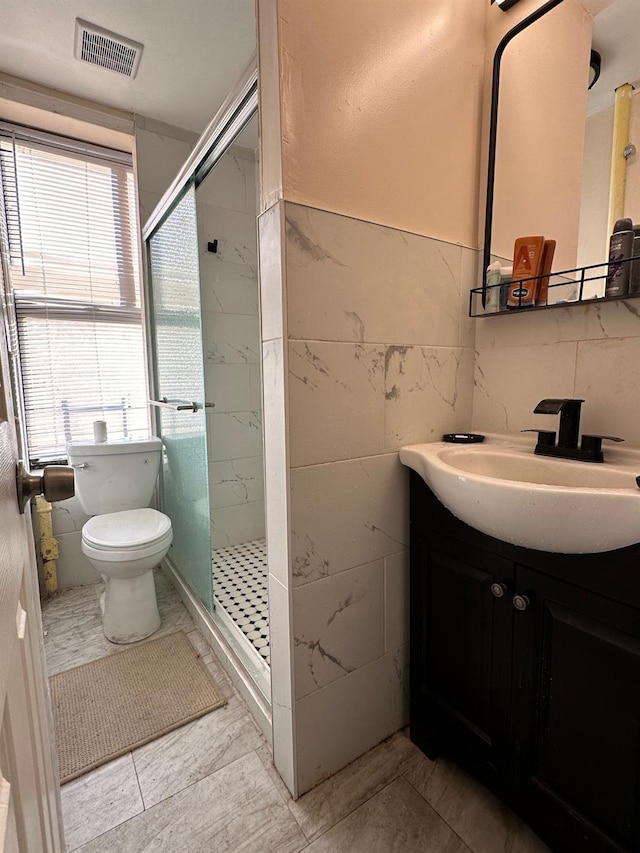 full bath featuring vanity, visible vents, toilet, tile walls, and a stall shower