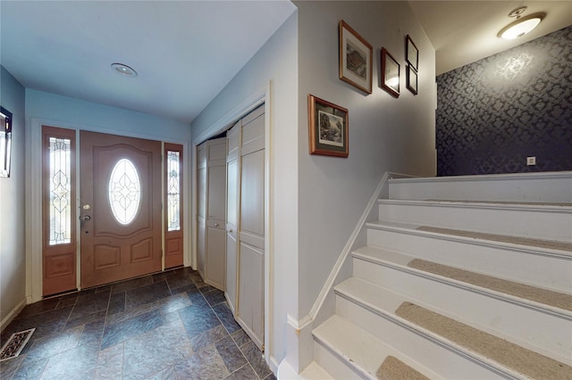 entryway with baseboards, stone tile floors, stairs, and visible vents