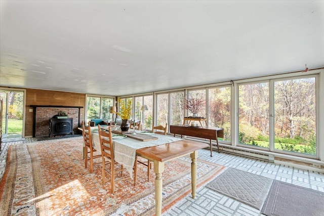 sunroom / solarium with a wood stove, a healthy amount of sunlight, and a baseboard radiator