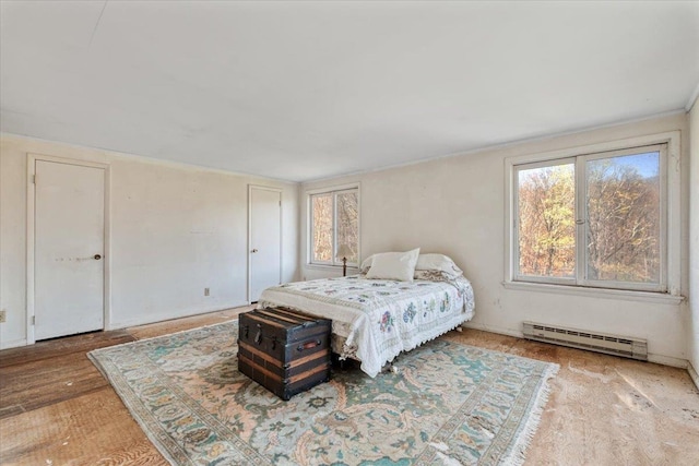 bedroom featuring wood finished floors, multiple windows, and a baseboard radiator