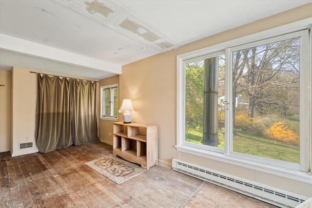 interior space featuring baseboard heating, visible vents, hardwood / wood-style floors, and baseboards
