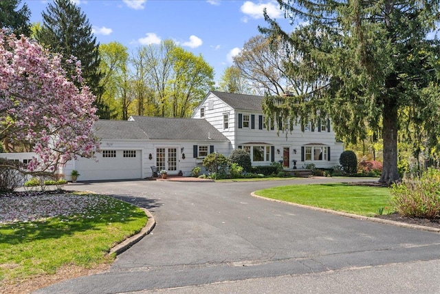 colonial inspired home featuring an attached garage, driveway, and a front lawn